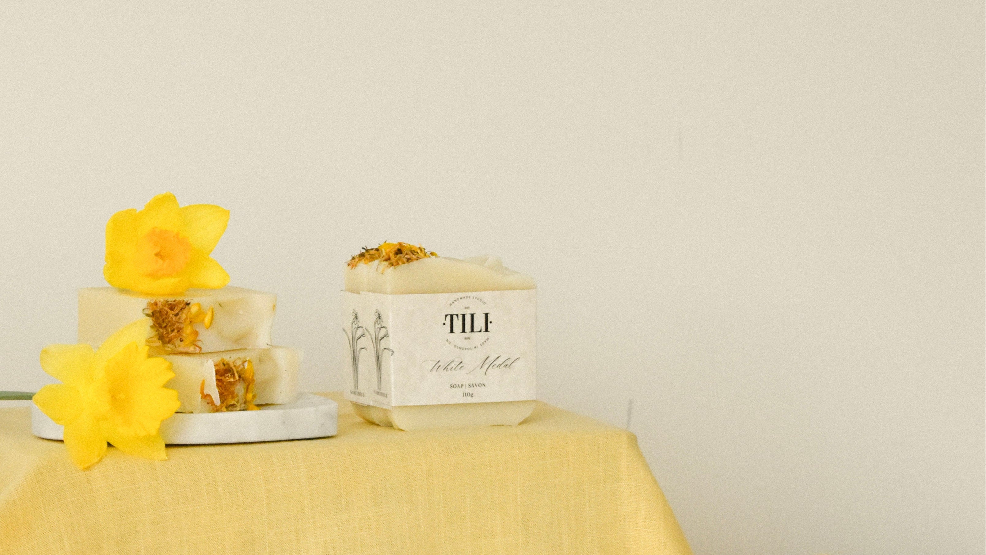 Yellow tablecloth with tili soap and decorative items on a plain background